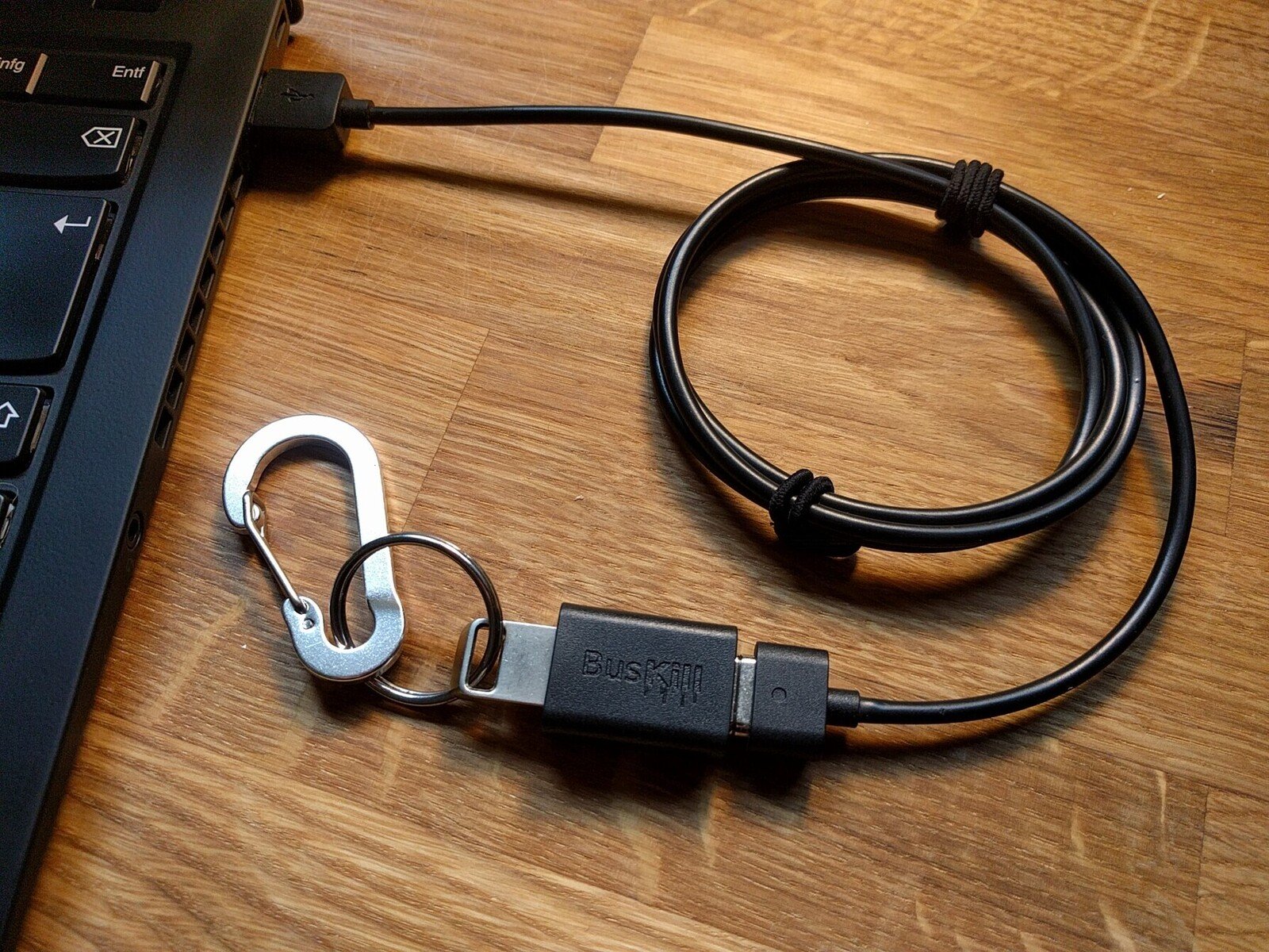 The assembled BusKill cable is plugged-into the USB-A port of a laptop